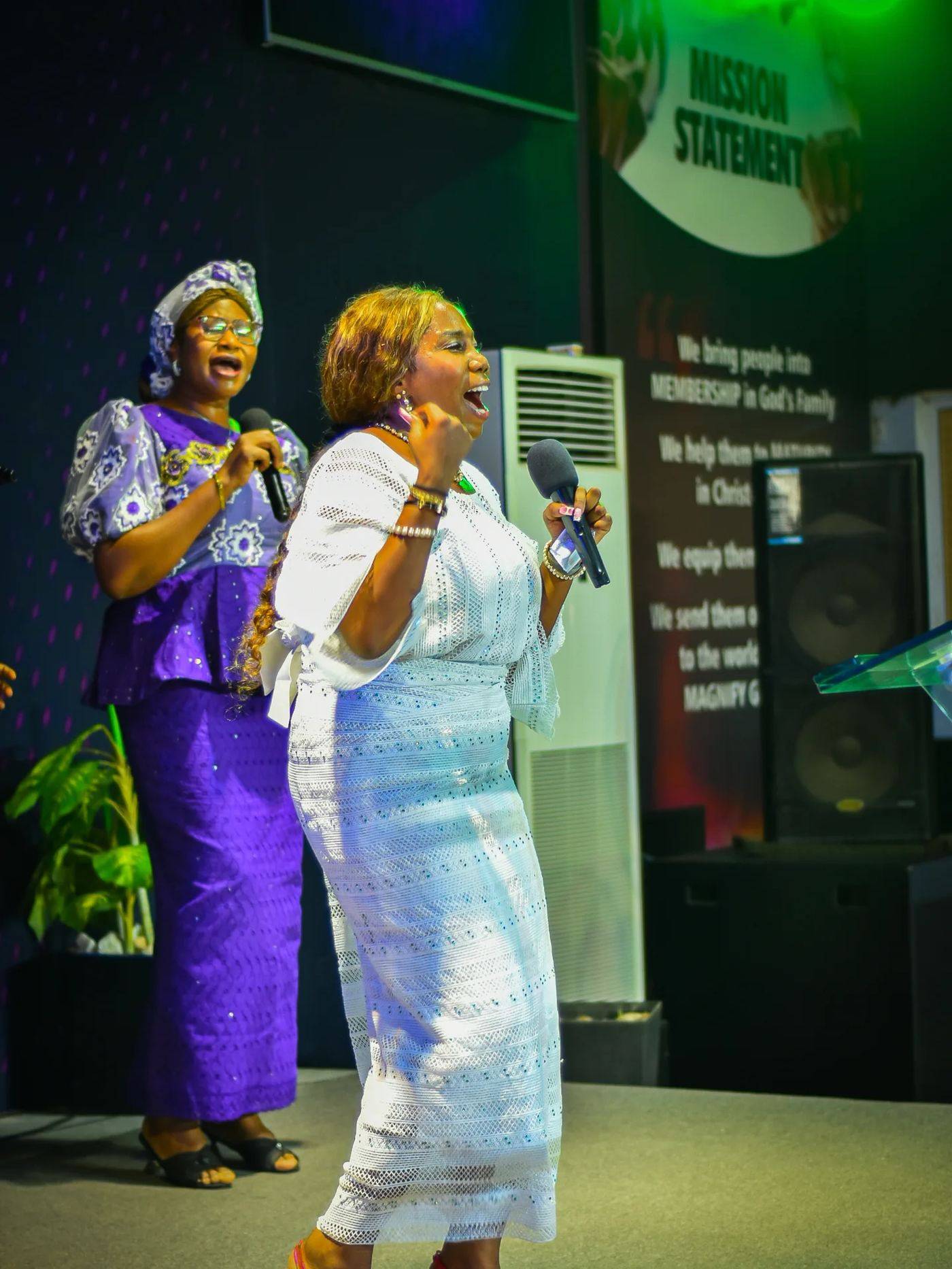 Ministers leading worship in front of The Stone Church's mission statement banner